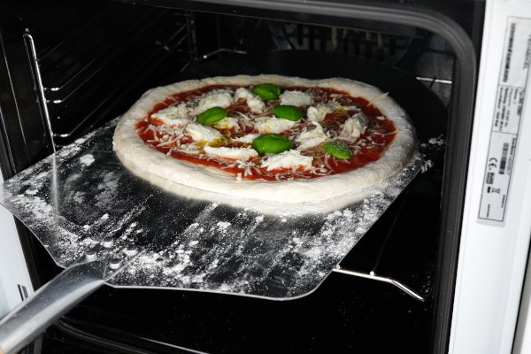 Pizza in den Ofen schieben