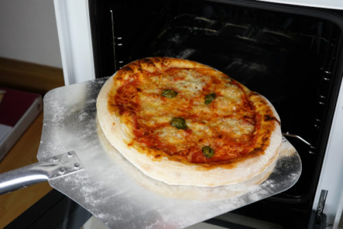 selbstgemachte Pizza aus dem Ofen holen